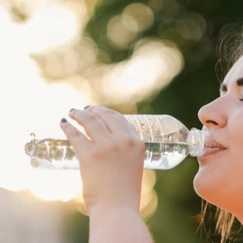 Vrouw water plastic fles zon roze shirt change inc adobe stock